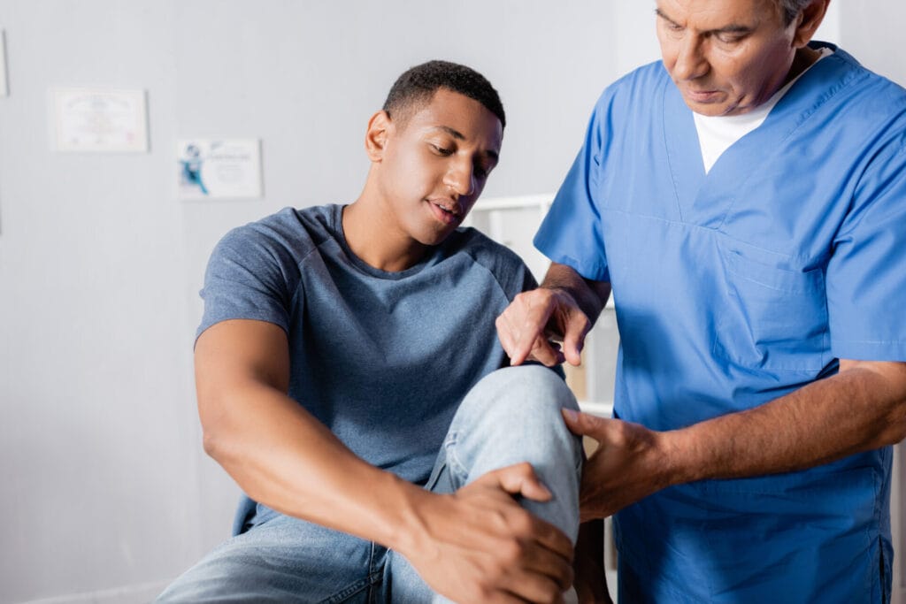 male patient with doctor examining knee