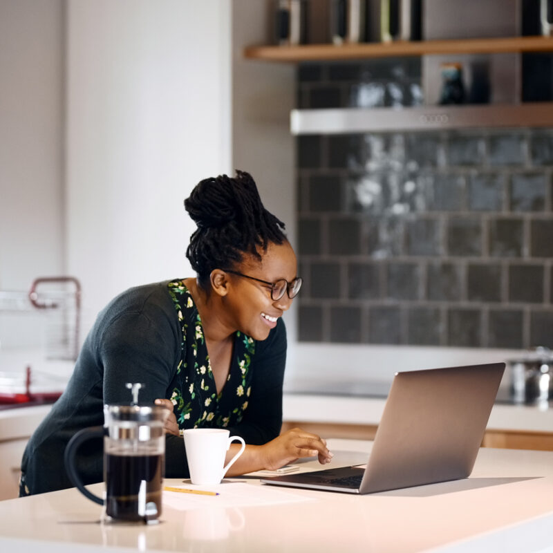 woman standing at table with laptop open