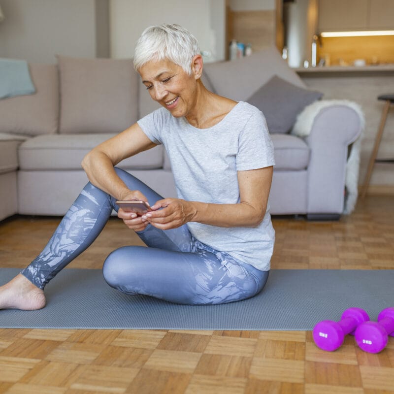 elderly woman sitting on floor looking at smartphone to check medicare advantage digital